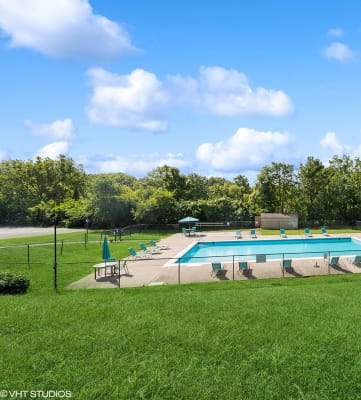 a swimming pool in the middle of a grassy field with a fence around it