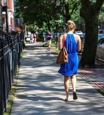 a woman in a blue dress is walking down a sidewalk
