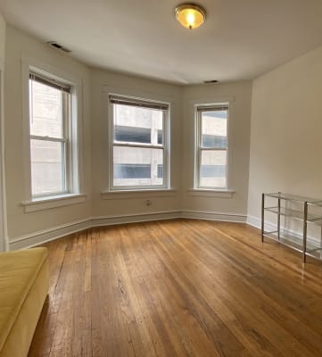 an empty living room with three windows and a couch