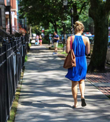 a woman in a blue dress is walking down a sidewalk