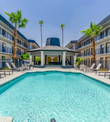 a swimming pool with chaise lounge chairs and a building in the background