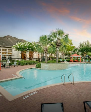 a resort style pool with lounge chairs and umbrellas