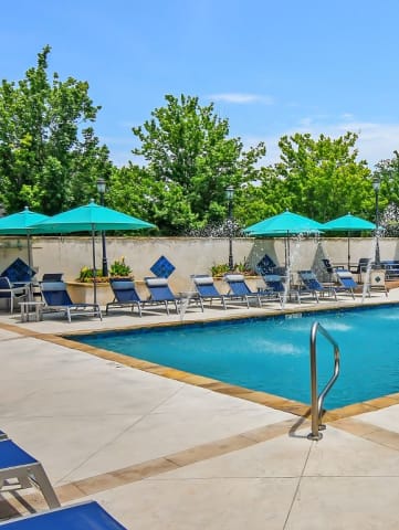 a swimming pool with blue lounge chairs and umbrellas