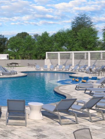 a swimming pool with chaise lounge chairs and a pool house in the background
