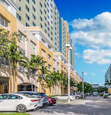 a city street with tall buildings on either side and cars parked on the side of the street