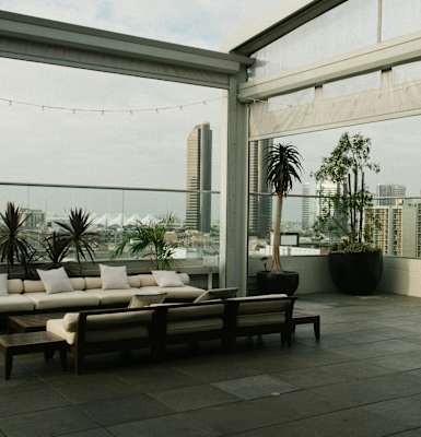 A rooftop patio with a couch, chairs, and a view of the city.
