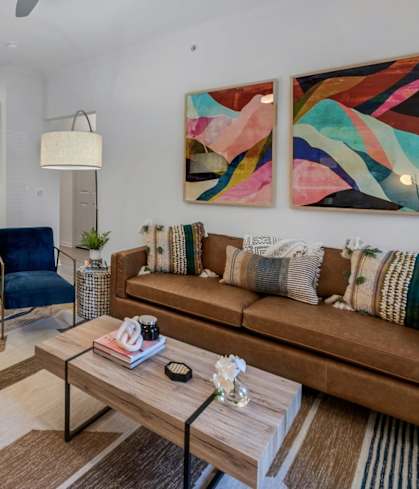 a living area with a couch coffee table and a kitchen in the background