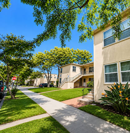 A sunny day in a quiet residential street with apartment buildings on either side.