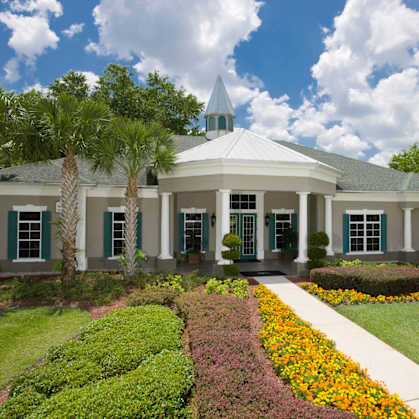 a large white building with a green lawn and a flower garden in front of it at Audubon Oaks, Lakeland, Florida
