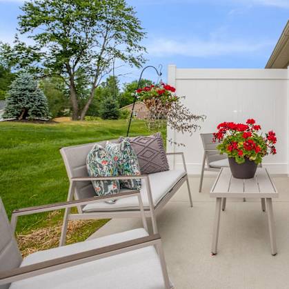 A patio with a table, chairs, and a potted plant.