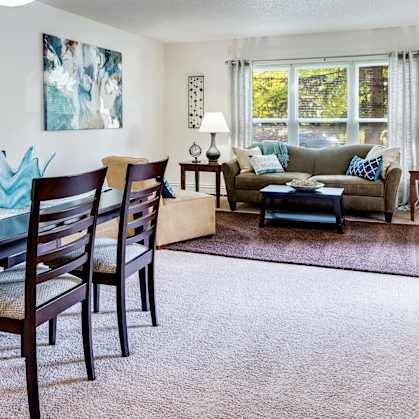 a living and dining room area with a table and chairs and a couch in the background