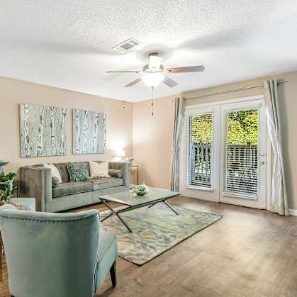 a living room with couches and chairs and a ceiling fan at Avalon Apartment Homes in Starkville, MS 39759