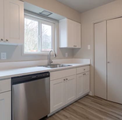a kitchen with white cabinets and a stainless steel dishwasher