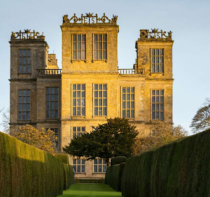 the side of a castle with hedges in front of it