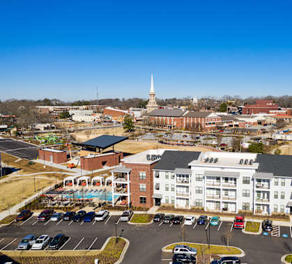 an aerial view of an apartment complex with a church steeple in the background at The Flats at Southlawn Apartments, GA