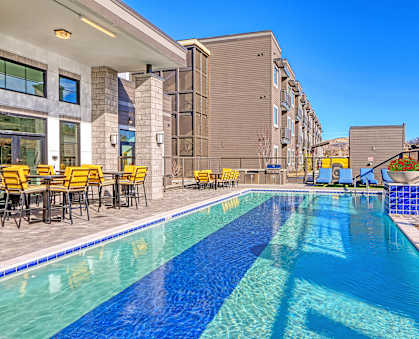 a swimming pool with tables and chairs next to a building