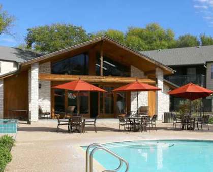 A large house with a pool and patio furniture.