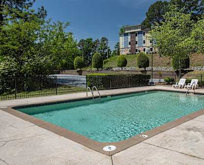 a swimming pool with chaise lounge chairs and trees in the background