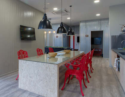 a kitchen with a long island and red chairs