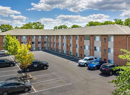 a parking lot with cars in front of an apartment building