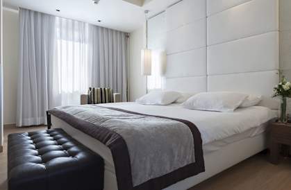a bedroom with a bed and a leather ottoman