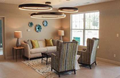 A living room with a striped chair and a couch.