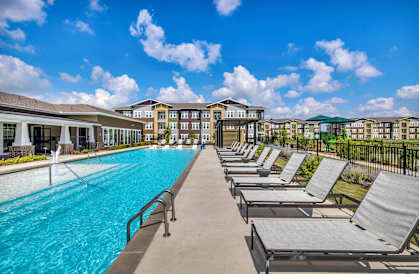 a swimming pool with chaise lounge chairs and a building in the background