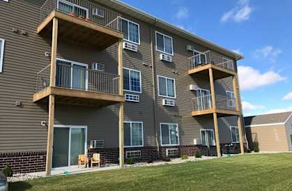 a building with three balconies and a grassy area in front of it at Courtyard Apartments, Moorhead, Minnesota