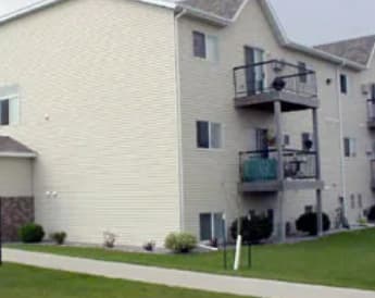 A white two story apartment building with a balcony on the second floor.