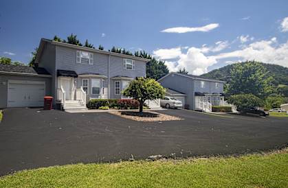 a house with a parking lot and a mountain in the background