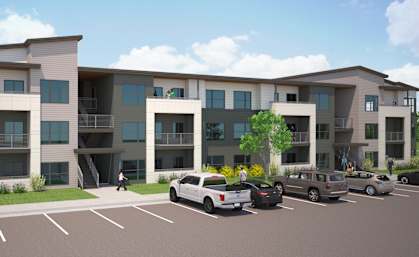 A modern apartment complex with a parking lot in front.