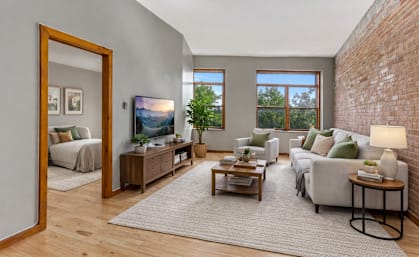 A living room with a grey couch, a wooden coffee table, and a large mirror.