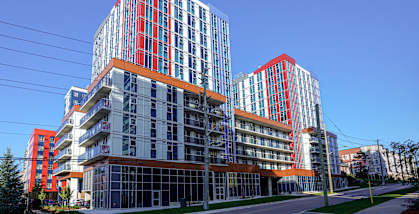 A modern building with red and blue accents stands tall against a clear blue sky.
