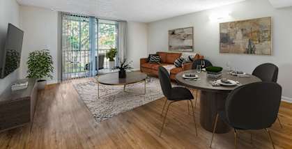 an open living room and dining room with a large sliding glass door leading to a balcony