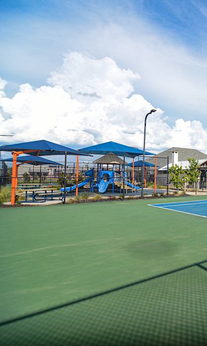 two tennis courts with houses and a playground in the background at Reserve of Bossier City Apartment Homes in Bossier City, Louisiana
