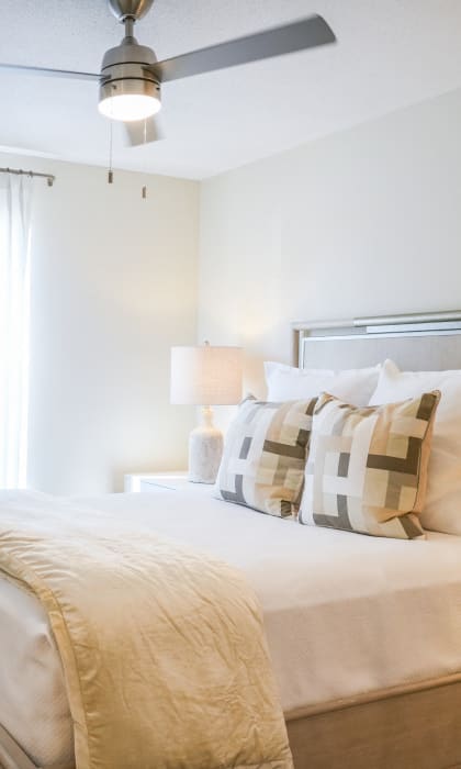 a bedroom with a large bed and a ceiling fan at The Vineyard at Castlewoods Apartment Homes in Brandon, Mississippi