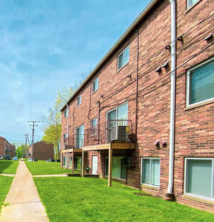 Sidewalk with grass between two brick apartment buildings