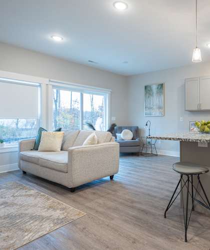 A kitchen with a white couch and a table with a bowl of fruit on it. at Eden Forest Townhomes Apartments, Kentwood , 49508