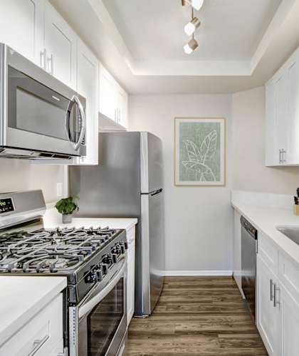 A kitchen with white cabinets and a stove top oven.