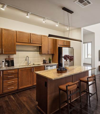 A modern kitchen with wooden cabinets and a bar area.