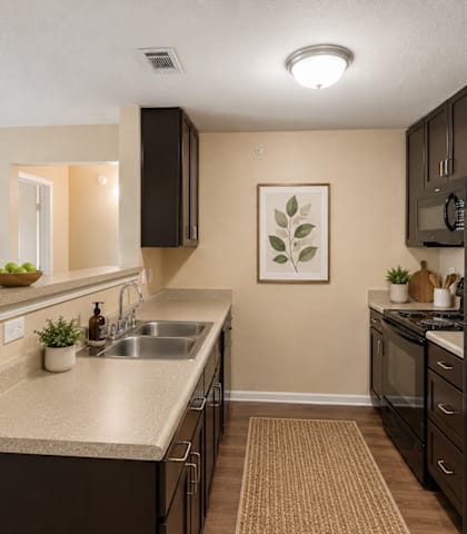 A kitchen with a black refrigerator and brown cabinets.