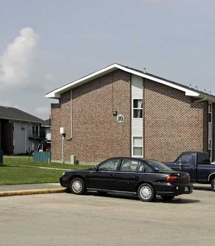 A black car is parked in front of a brick building.