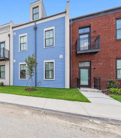 A row of three-story townhouses with balconies and front yards.