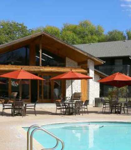 A large house with a pool and patio furniture.