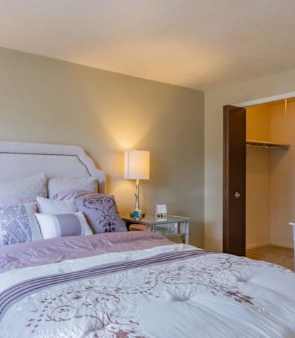 A bedroom with a large bed and two lamps.