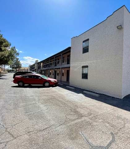 A red car is parked in front of a white building.