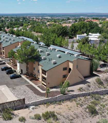A building with a green roof is surrounded by a parking lot.
