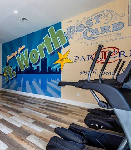 a home gym with a wall mural and exercise equipment