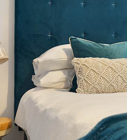 a bedroom with a blue headboard and a bedside table with a vase of flowers