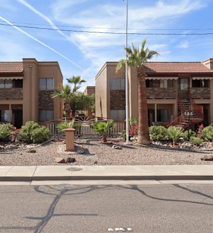 A row of houses with red roofs and palm trees in front.
